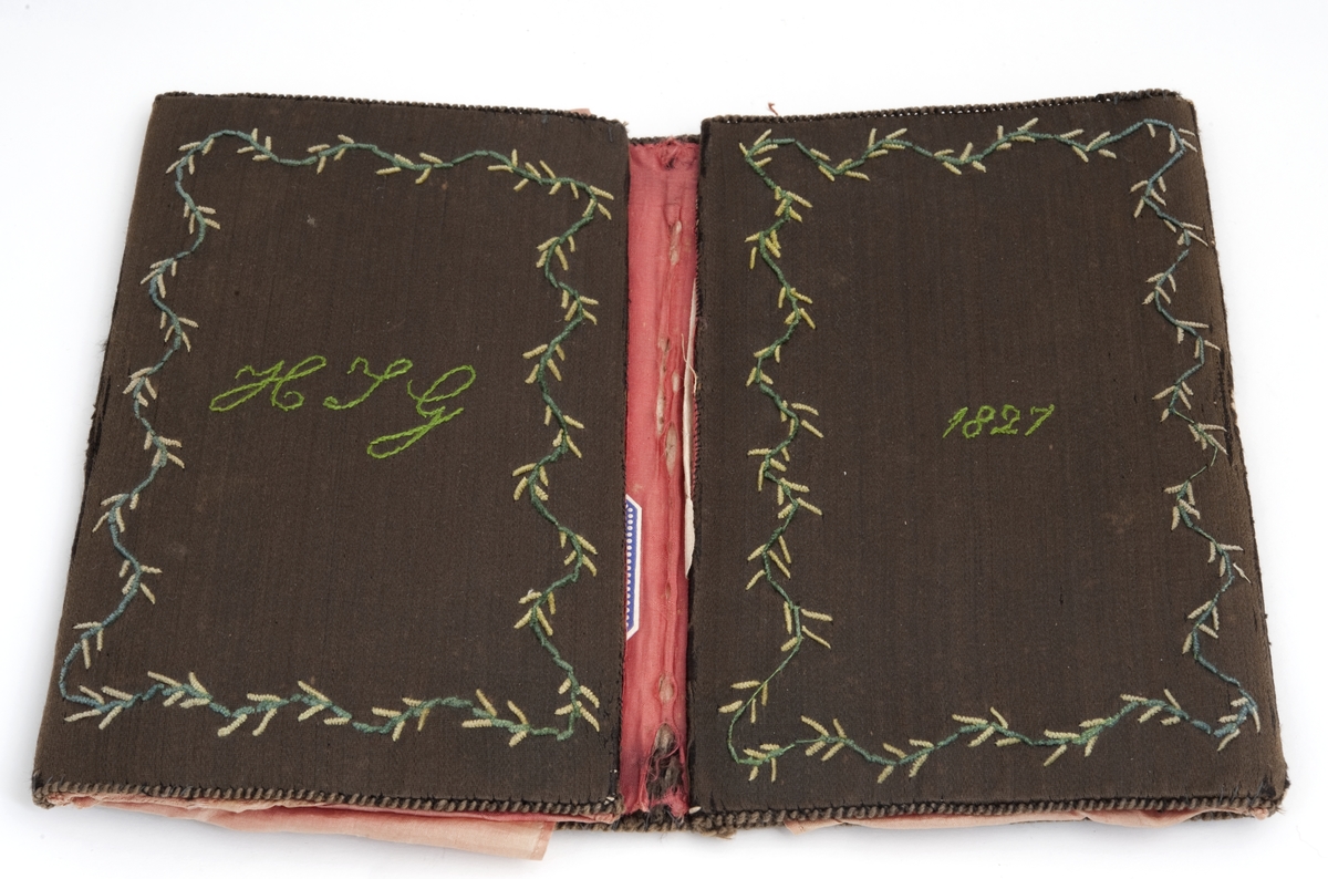 En brodert lommebok.
Påbrodert H. J. G. - 1827, grønn silke, broderte blomster med rødt for.
Efter Hans Jacob Grøgaard.