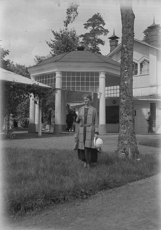 Porla brunn, en kvinna framför byggnaden.