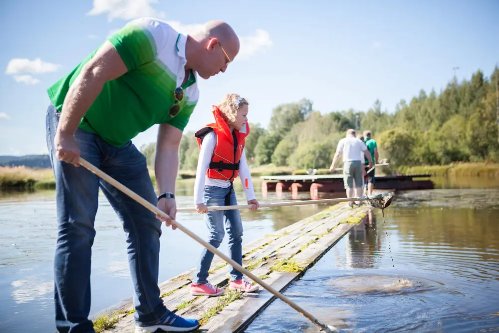 Foto av en far og datter som fanger insekter i vann