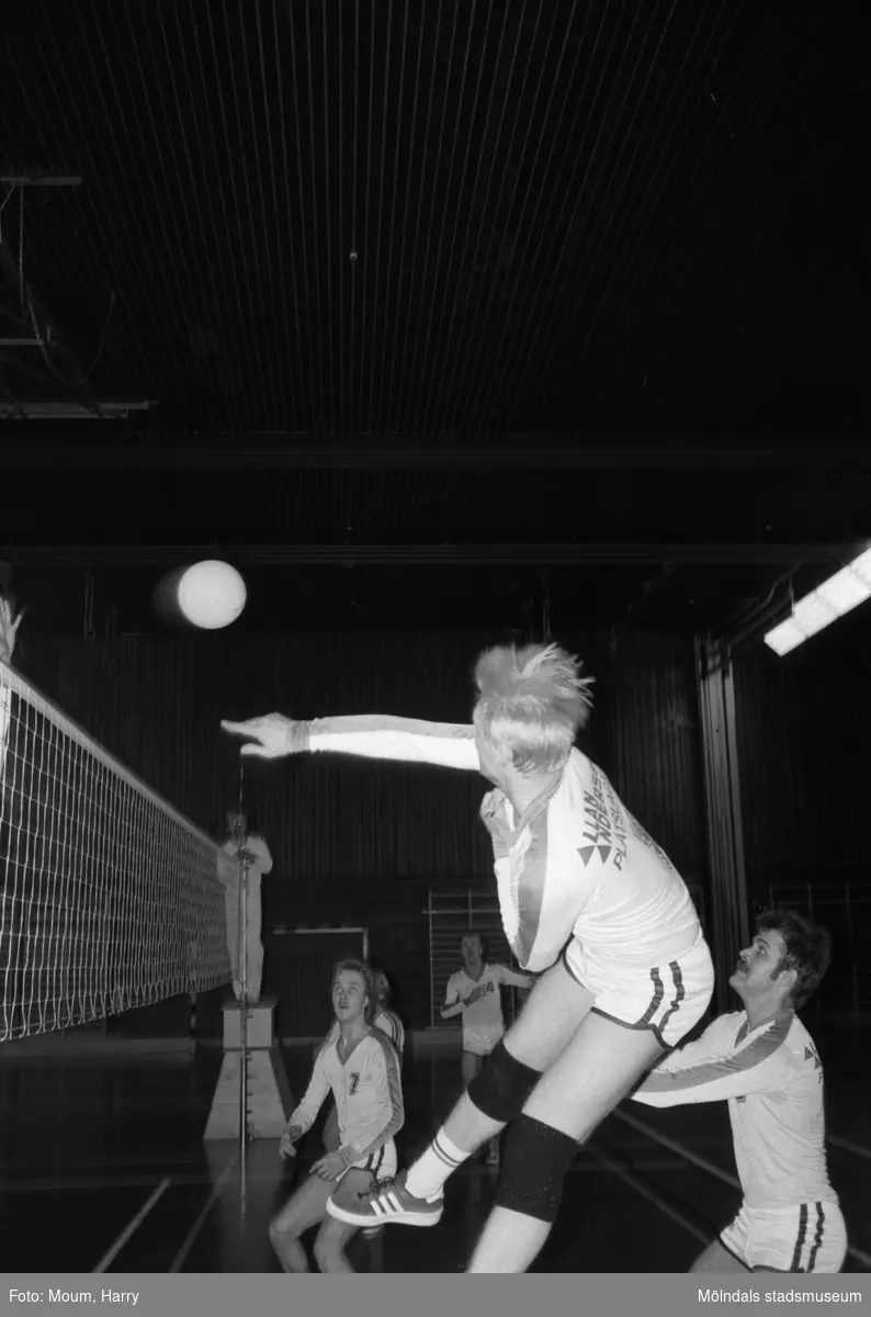Volleybollmatch mellan de båda lindomelagen Lindome Finska Förening och Trevaren i Ekenskolans idrottshall, Kållered, år 1984. "Not: På vidstående bild av HUM är det Lindome som "trycker" på."

För mer information om bilden se under tilläggsinformation.