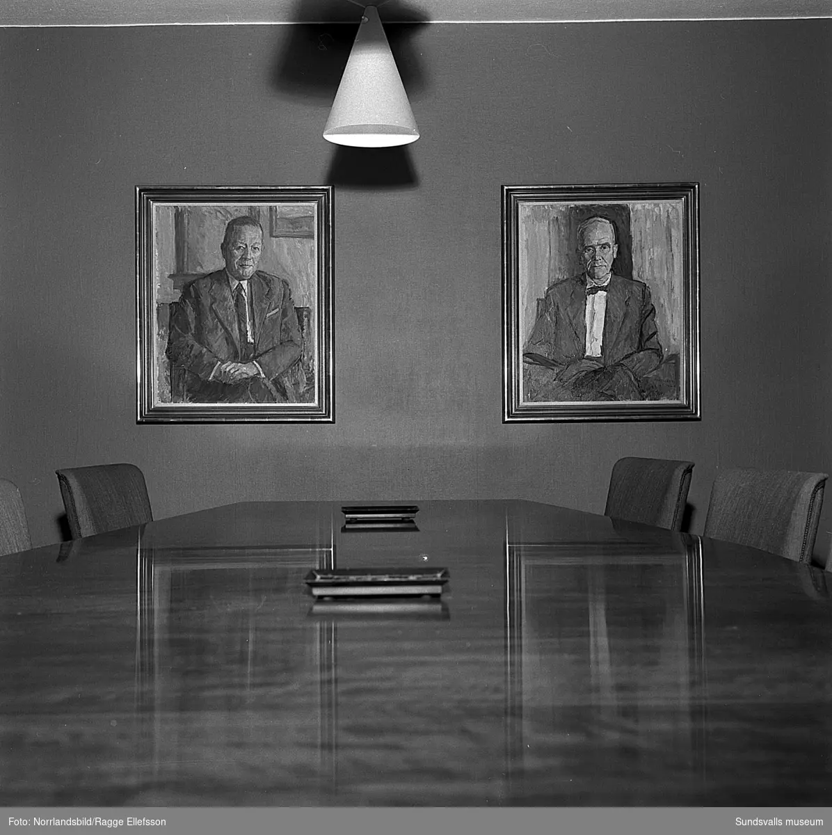 Direktörerna Anders Nisses och Per Hallström vid sina porträtt i kontorshuset vid Landsvägsallén.