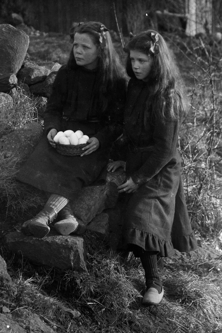 Barnporträtt. Fotografens två systrar Signe, med en kanin och Lydia med hönsägg på ett fat - symboler för påsken. 1910-tal.