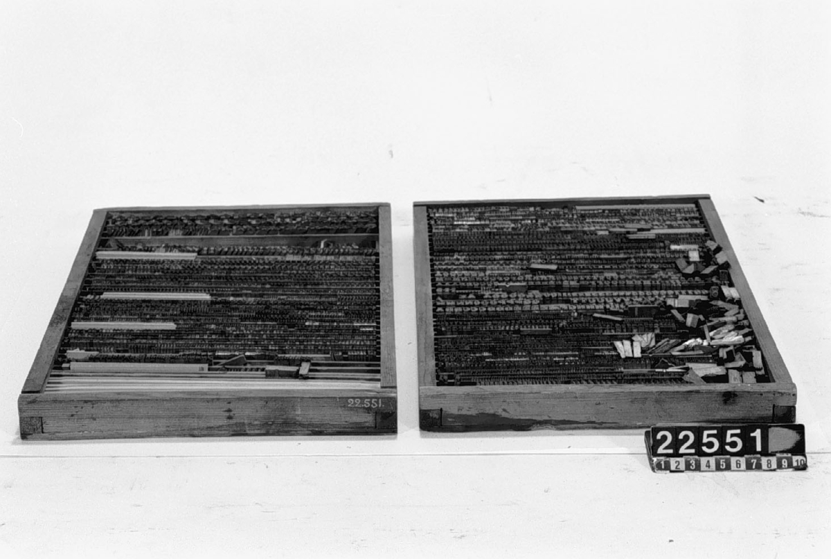Digelpress jämte stilsatser och skåp med lådor. Två st. träramar med typer. a) 400 x 250 mm, vikt: 8,1 kg. b) 400 x 250 mm, vikt: 9,6 kg.