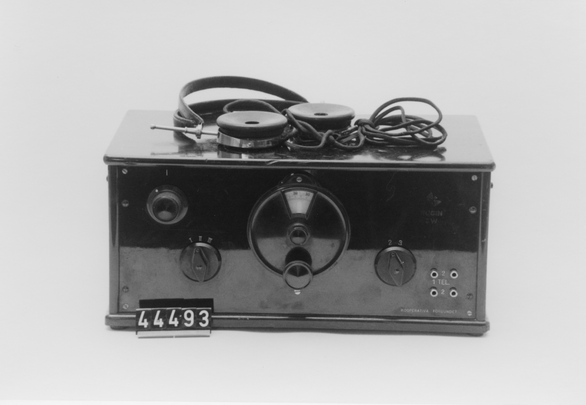 Batteridriven radiomottagare med uttag för hörlurar. Trähölje med bakelitpanel med rattar framtill.
HUGIN 3W, nr 8279, telefunken marconi licensnr 71368.