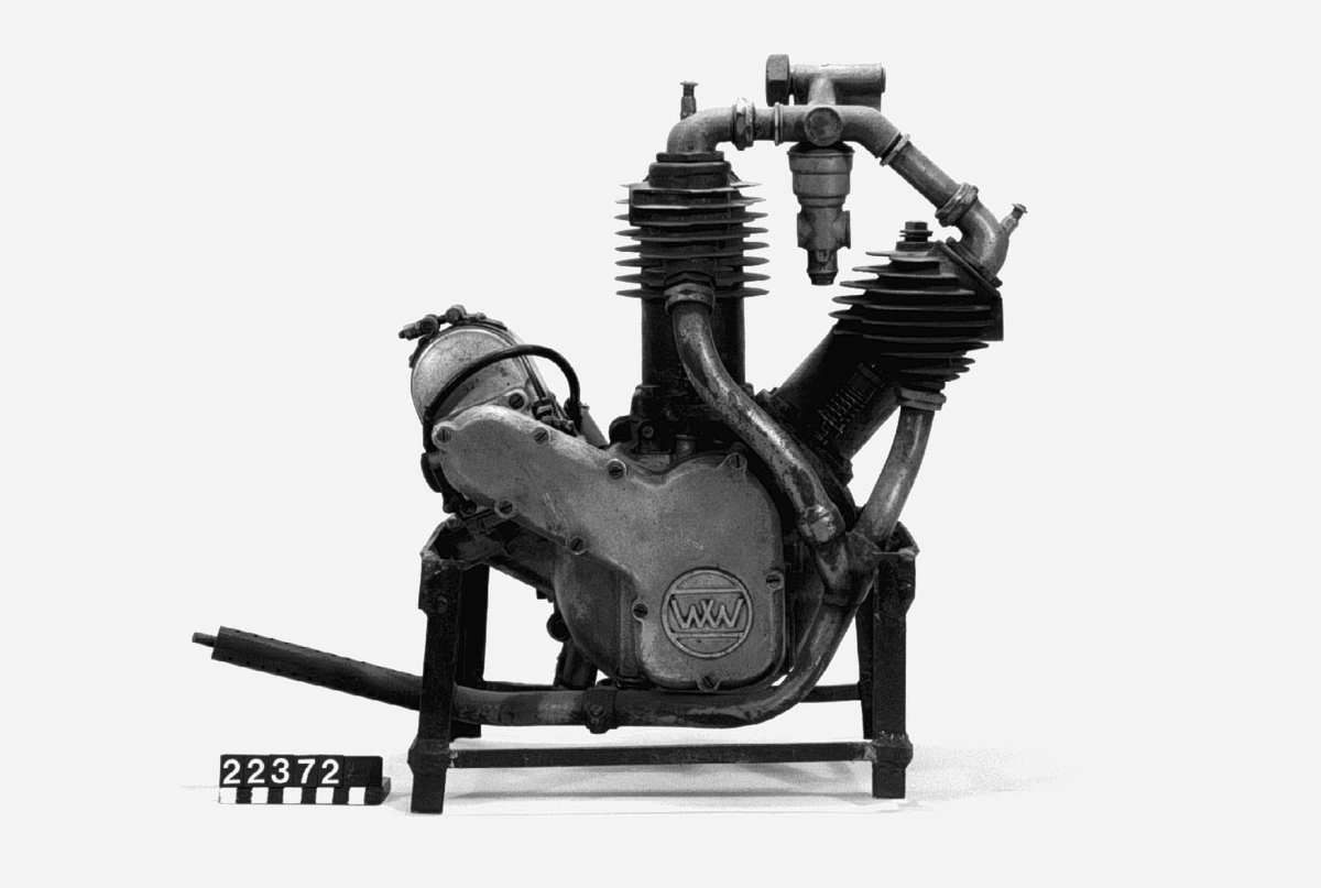 Motorcykelmotor omkring 1915. Bensinmotor med remskiva för kilremsdrivning till bakhjulet. Ställbar koppling. Bosch magnet. Motornummer 13163 H.  Tvåcylindrig luftkyld fyrtaktsmotor, cylindervolym 408 cc En cylinder har sidventil, en snarkventil Effekt 4 hk vid 800 - 1 000 varv/minut