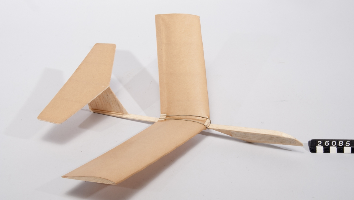 Glidflygplansmodell i balsaträ och papper. Vingen fastsatt med gummiband, flyttbar för att möjliggöra varierbar tyngdpunkt.