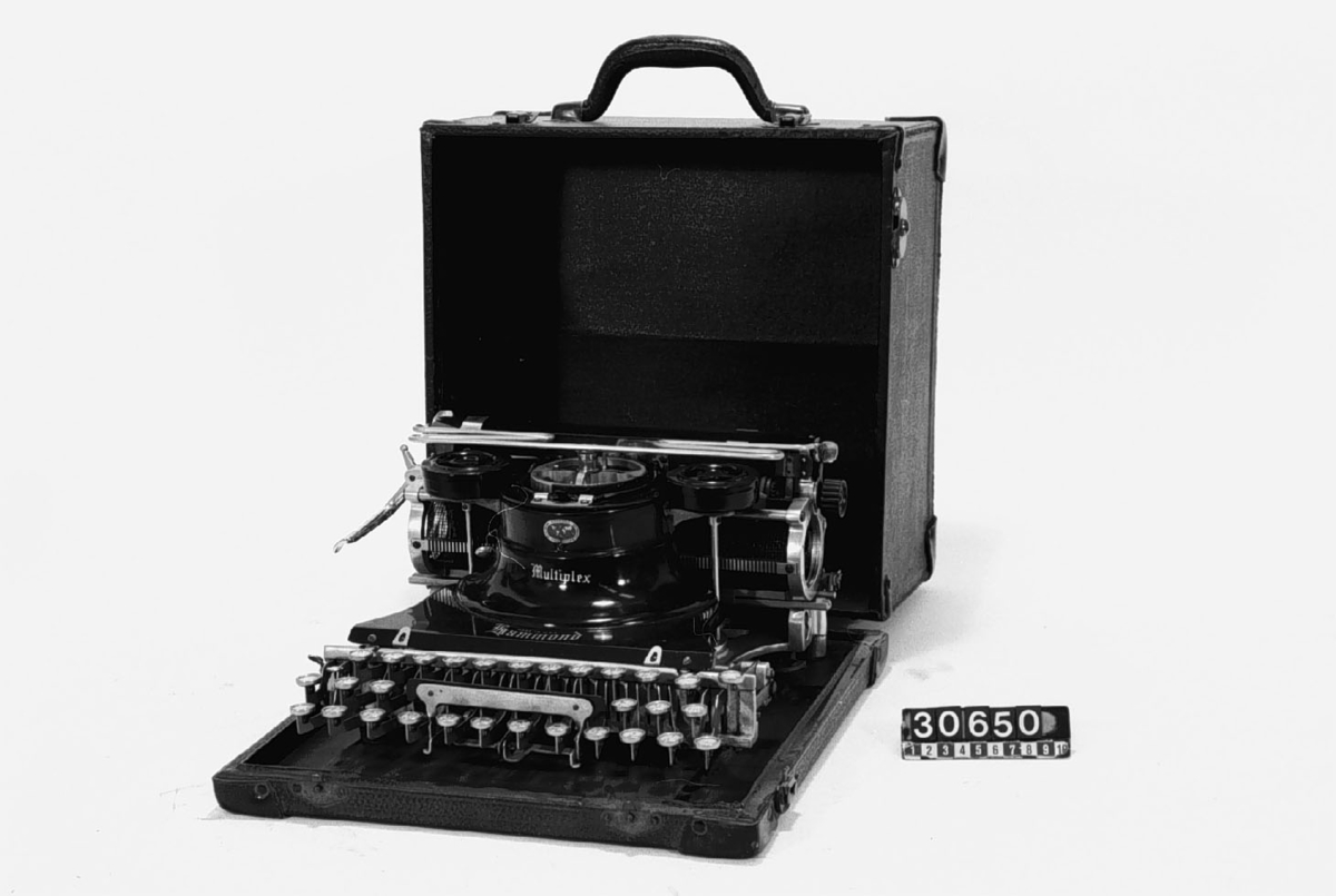 Svart skrivmaskin i en låda med hölje av pergamenterat trä. Maskinen är fastskruvad i lådan. Typer till mask, se TM 33.822-24.
Tillbehör: Låda.