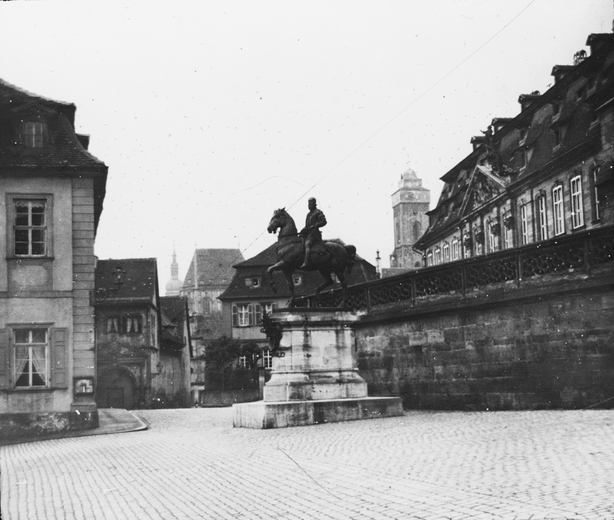 Skioptikonbild med motiv av okänd staty på torg i Bambeg.
Bilden har förvarats i kartong märkt: Resan 1906. Bamberg 8. Text på bild: "Vickes pl.".