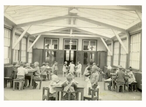 Leksalen i gamla träpaviljongen på Kustsanatoriet Apelviken. Grupper av barn sitter kring bord.