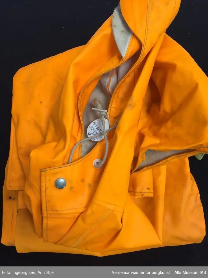 Oransje jakke med hette og bukse med seler.