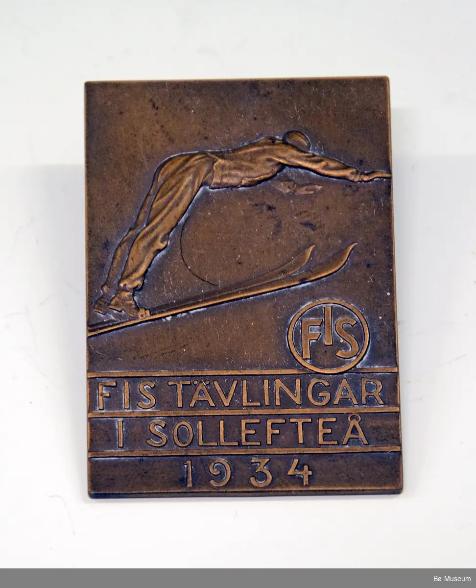 Deltakermedalje, "minnemynt". Fra Sollefteå, Sverige. FIS-hopprenn i 1934. Medaljen er laget av bronse, og ligger i etui.
Innskrift: FIS TÄVLINGAR I SOLLEFTEÅ 1934.