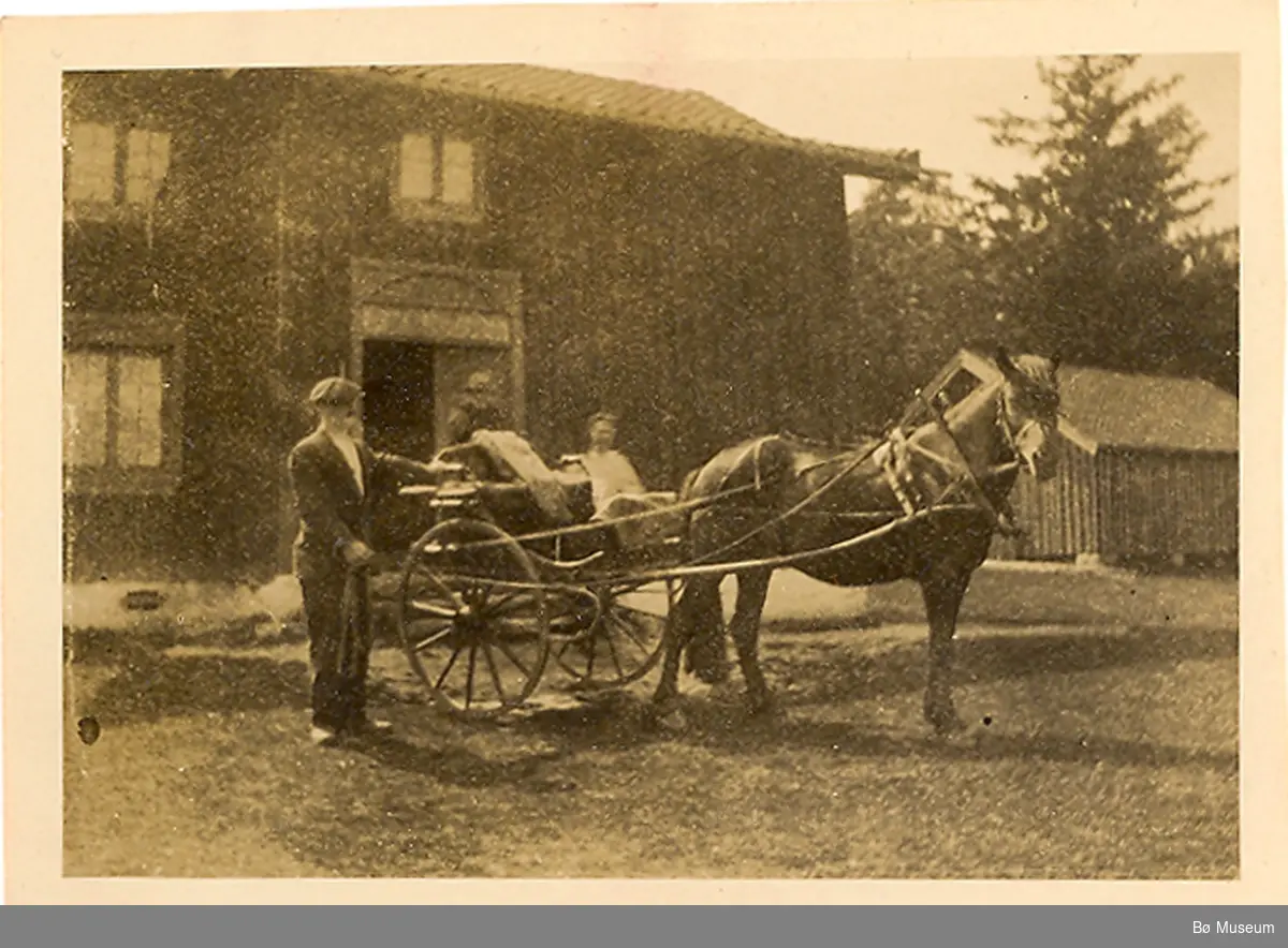 Foto 1923. Mann med hest og kjerre i gardstun.