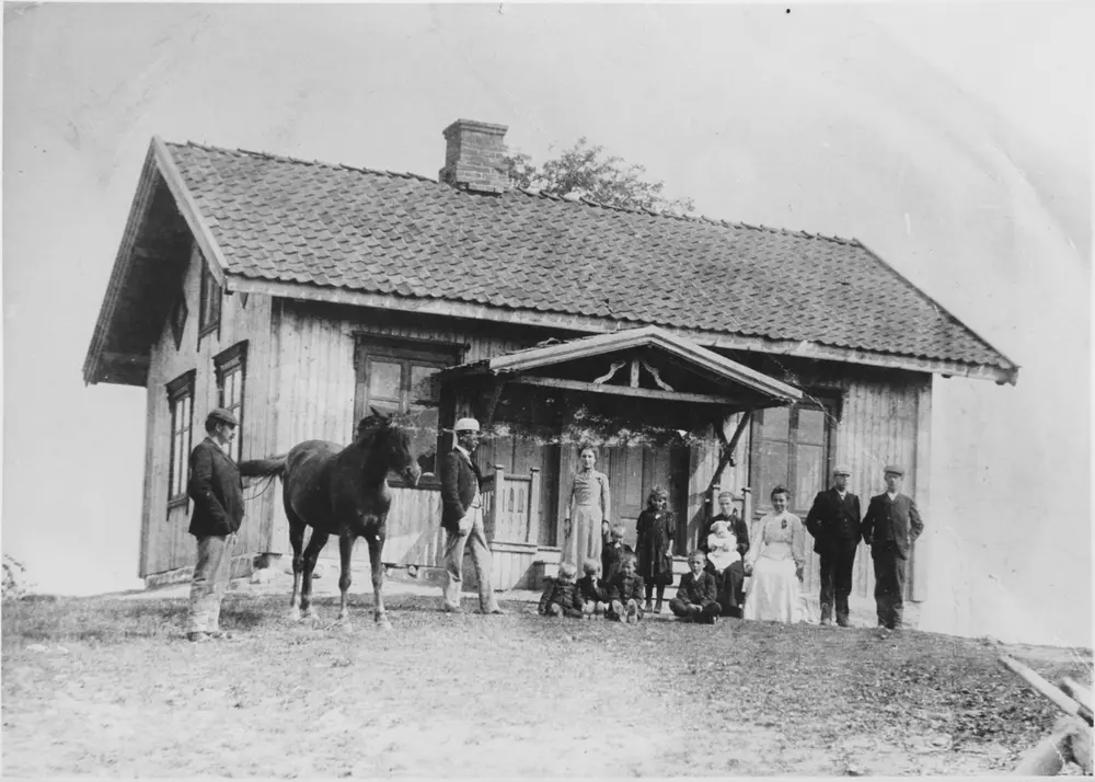 Gruppebilde på husmannsplassen Løkkeberg, fra venstre: skredder Karl Caspersen Lie, Johan Nordby, Emma Tyrihjell, sittende: Erling, Rolf, Henry og Arthur Lie, Thora Lie (f. 1900), Kitty Lie (g. Løken), sittende Anette Lie med Signe Lie på fanget og Emma Lie (g. Torp), skredderne Johan og Gulbrand Årnes.