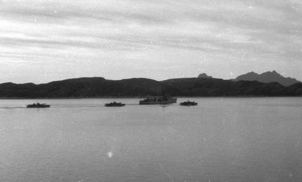 Landskap. Flere militære farkoster på vei inn mot Bodø havn. I bakgrunn Hjertøyene og Landegode.