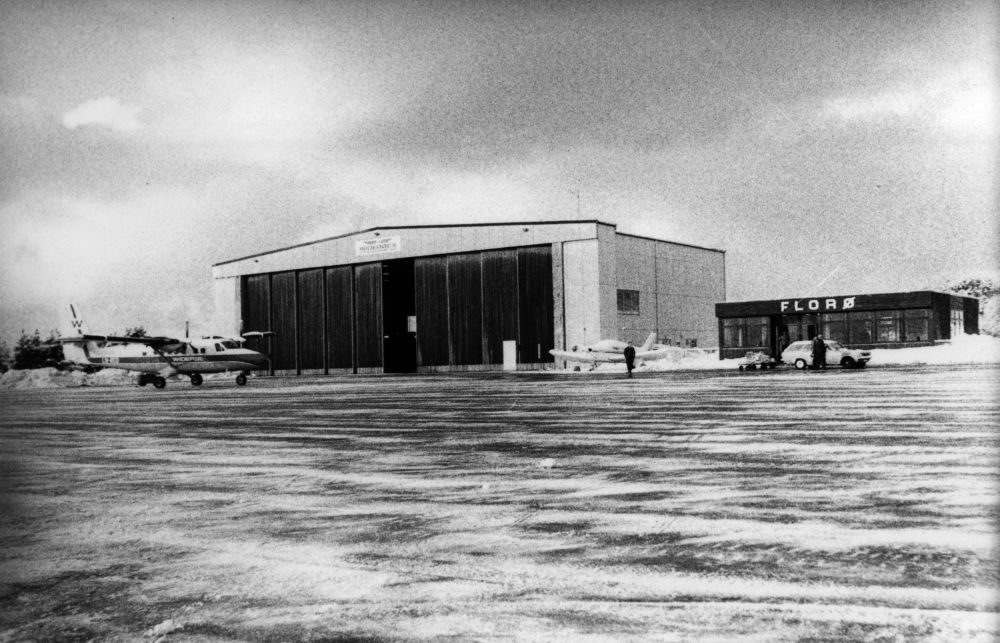 Lufthavn/Flyplass. Flora. To fly, en DHC-6 Twin Otter fra Widerøe og et nedsnødd småfly, parkert foran hangaren. Ved siden av ligger Widerøes flyekspedisjon.