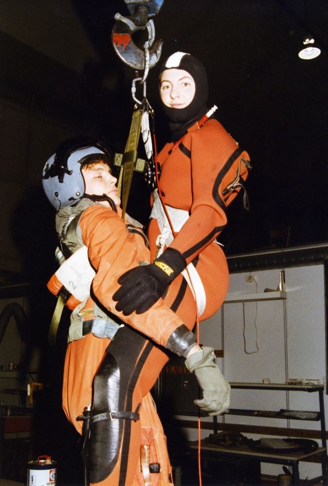 Lufthavn/Flyplass. Bodø. Flyhangar. To personer demonstrerer bruken av redningsutstyr som benyttes i Redningshelikopter.