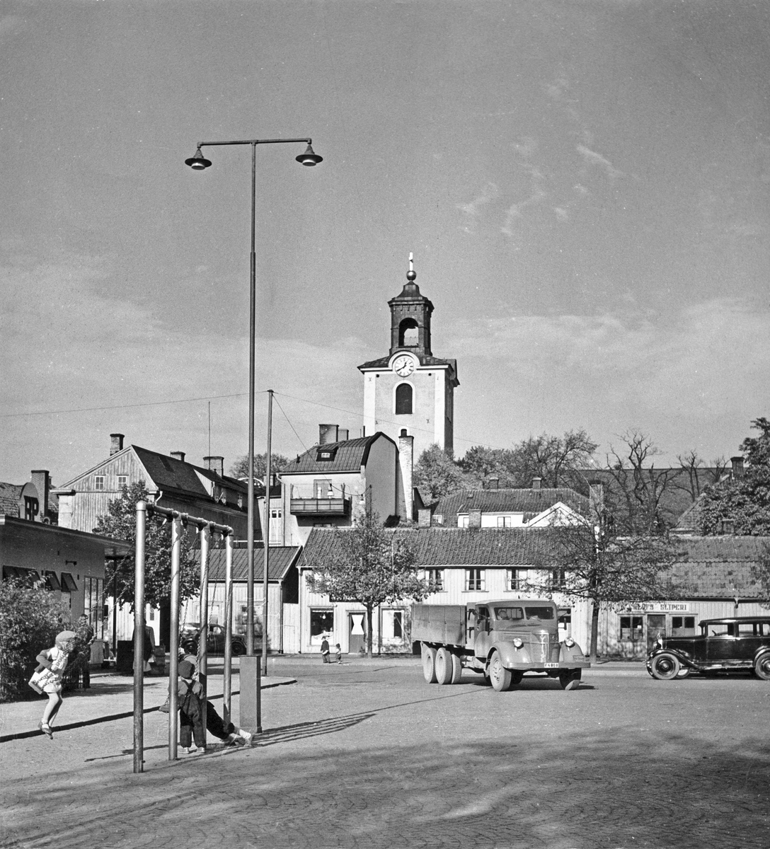 På Östra torget i Jönköping har man satt upp gungor för stadens barn. Kristinakyrkans torn syns i bakgrunden.
