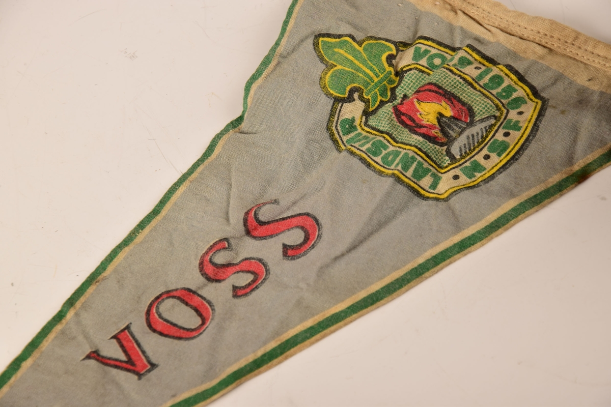 Vimpel fra landsleiren i Voss i 1956. 

Lik tekst og dekor på begge sider av vimpelen. Snor i enden.