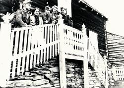 Tre soldater og to kvinner stå i trappa ved inngangen til ei