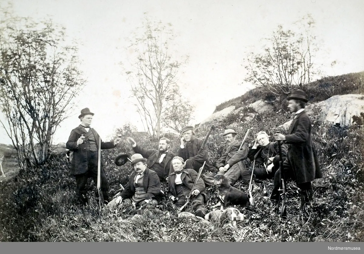 "Jagtklubben til Hr N. R. Parelius". Bildet viser her jaktlaget til Niels Rosing Parelius (f.1813 - d. 1879), og vi finner ham muligens som nummer tre fra høyre i øverste rekke. Bildet er trolig fra 1860 til 1879, og fotograf er ukjent. Fra Nordmøre Museums fotosamlinger.