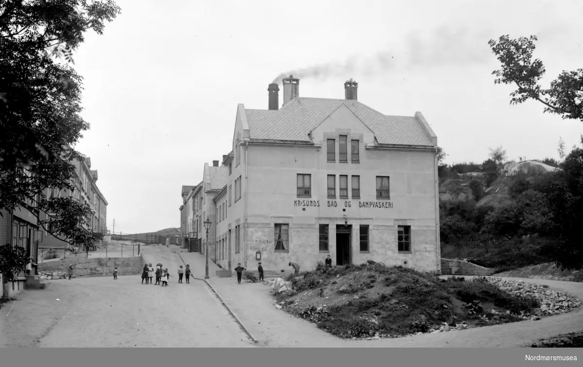 Et bilde fra Kristiansunds bad og dampvaskeri, som lå ved Barmannhaugen på Kirkelandet i Kristiansund. En "badehuskomite" som ble satt ned sørget for at i 1908 stod ferdig et kombinert bade- og dampvaskeri samt badstue, og prisene var 1 krone for 1. klasse og 25 øre for 2. klasse. Badet var en selveiende institusjon, og fikk vederlagsfritt bruke en viss mengde vann, mot gratis adgang for skolebarn. Bruken av bygget anslås for å være ikke så stor, da det er antatt at bare 10 % av befolkningen benyttet seg av badet. Badet overlevde bybrannen under tyskernes herjinger i aprildagene 1940, og stod helt frem mot år 2000, da bygget ble revet og brukt til parkeringsplass for Nordmøre Sparebank. Senere har det kommet boliger på eiendommen (per 2007).  Bildet er fra Nordmøre museums fotosamlinger. Kilde: Eivind Aass: Kristiansunds historie VI, side 61. NorPro holdt til her inntil riving.