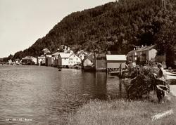 Postkort ";13-56-10"; fra strandlinjen med brygger og naust 