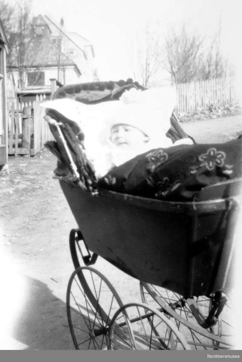 Overeksponert bilde av Ivar Rød i barnevognen rundt 1930. Fotograf er sannsynligvis et medlem fra Rød familien. I bakgrunnen ser vi Lasarettet ved sykehuset i Kristiansund. Ukjent datering, trolig mellom 1935 til 1939. Giver av bildet er Turid Rød. Fra Nordmøre Museums fotosamlinger. Reg: EFR
