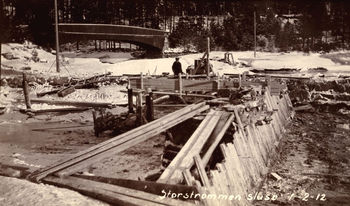Storstrømmen sluse. Nedre Fangdam. Vinter, snø, is, elv og en menn som arbeider. En bro og trær i bakgrunn. (Arkiv: Kanalvesenet/Vassdragsvesenet Uba-2-04)