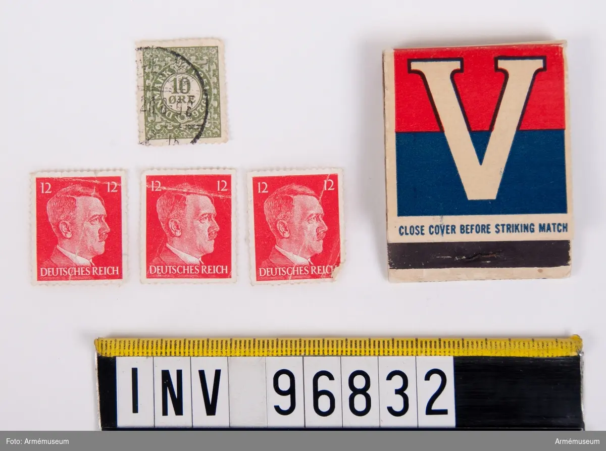 Tändsticksask innehållande tändstickor samt fyra frimärken, varav tre stycken tyska röda föreställande Adolf Hitler och ett grönt danskt med texten 10 ÖRE.