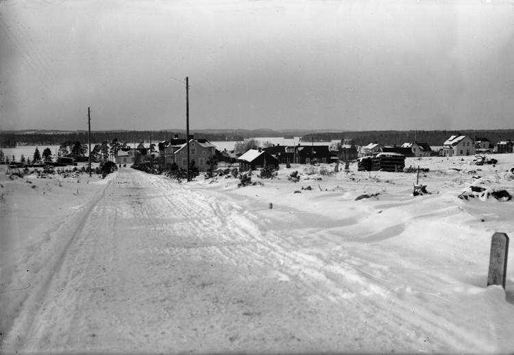 Vinterbild. Det syns några bostadshus och telefonstolpar. I bakgrunden ...