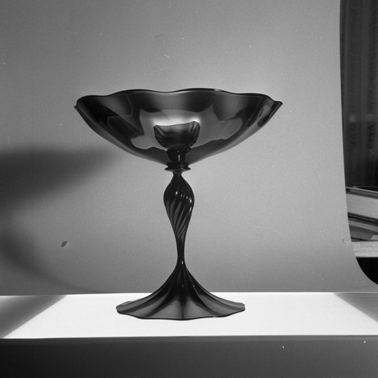 Foto av en skål av färgat glas, med ben och fot. S.k. slottsglas.