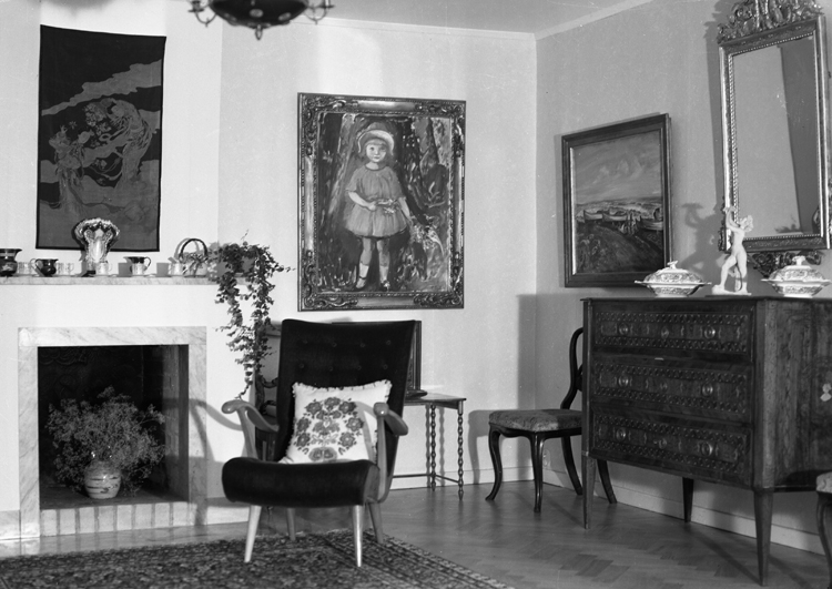 Foto från ett vardagsrum med öppen spis, en fåtölj, en stol och en byrå m.m.
Carl Ryd (1883-1958), konstnär, Lekaryd.
Carl Magnus Ryd, född 13 augusti 1883 Lekaryds församling i Kronobergs län, död 26 augusti 1958 i Lekaryds församling Han tillhörde konstnärsgruppen "De unga"
Han studerade för Carl Wilhelmson 1905 på Valand och 1906-1908 vid Konstnärsförbundets målarskola i Stockholm för Karl Nordström.
Han började studera för Henri Matisse men trivdes inte och lämnade skolan nästan genast. Han kom att vistas två gånger till i Frankrike, sommaren 1911 och åren 1920-1922. Han var 1919-1920 lärare och föreståndare vid Valands målarskola i Göteborg.
Han målade realistiskt och formstarkt, men även intimt tolkade porträtt, gärna av barn, samt framför allt lyriskt uppfattade landskap och vintermotiv, med äkta smålandsnatur, eller från skånekusten. Han målade även landskap från Öland, med gråstämda eller i blåaktiga och i rosa toner.
Han är representerad i Nationalmuseum, Moderna Museet, Thielska galleriet, Göteborgs Konstmuseum, Malmö Museum, Smålands museum i Växjö, Ystad, Kalmar, Gävle, Norrköping, Hudiksvall, Statens Museum för Kunst i Köpenhamn och Nasjonalgalleriet i Oslo.
Källa: Konstnärslexikonett Amanda. Sveriges Dödbok 1901-2009.