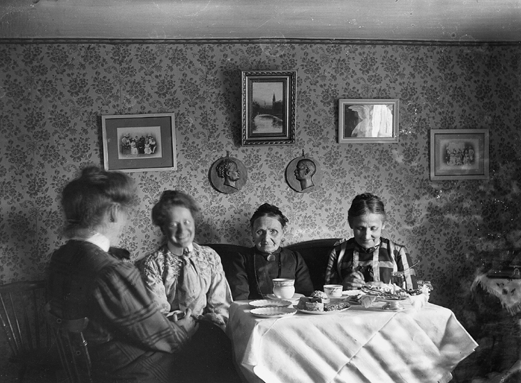 Några glada kvinnor har samlats kring ett kaffebord.