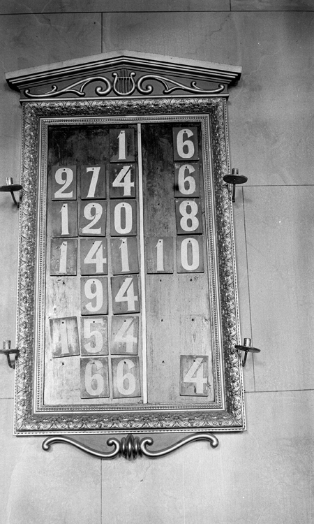 Foto av nummertavla, med ljushållare vid sidorna. 
Litt.: Smålandsposten 14/5 1932.