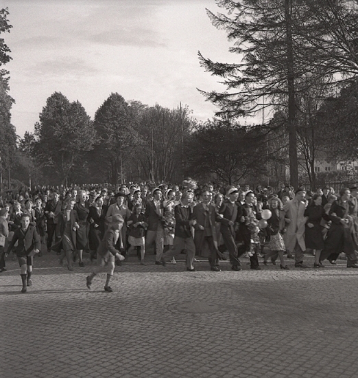 Studenterna 1940. 31/5 - 1/6. Studenter och anhöriga m.fl. på väg över järnvägen, mot Norra Järnvägsgatan. I bakgrunden skymtar dåv. Järnvägsrestaurangen (nuv. Domprostgården) till höger.