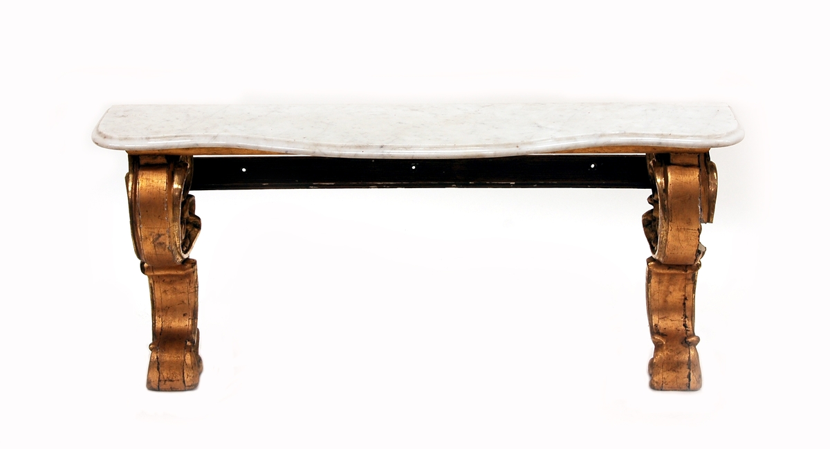 Kat.kort: Trymå, med skuren, belagd, förgylld ram, upptill överstycke, nedtill lågt bord med marmorskivor.