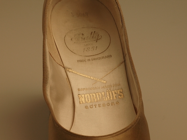 Damskor.
Ett par guldfärgade skor med klädd stilettklack. Delvis skinnfodrade.
Märkning i skon se "signering/märkning" ovan.
Sulan märkt 50.

Infört i huvudbok 1994.