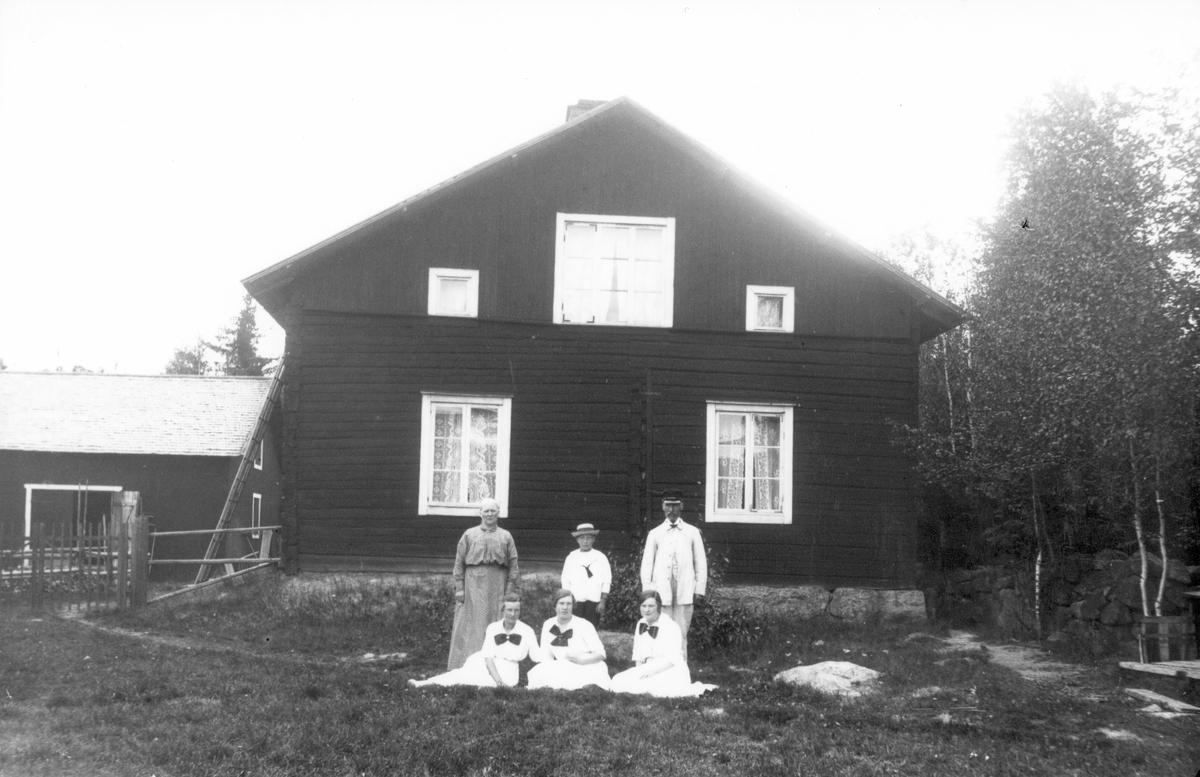 Familj samlad framför gårdsbyggnad. Foto 1917.