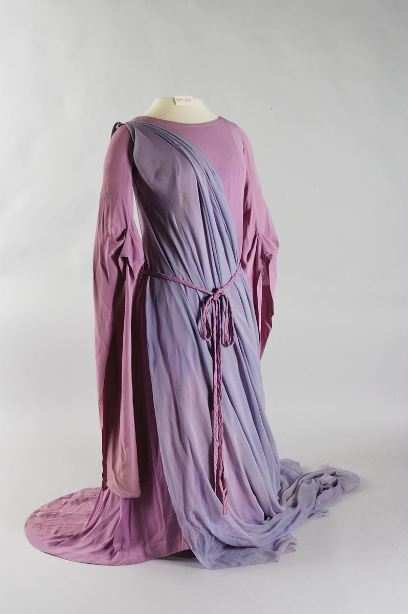 Kostyme Kirsten Flagstad i rollen som Isolde av Richard Wagners Tristan og Isolde. En rosa og lilla kjole med belte og lange ermer og langt slep.