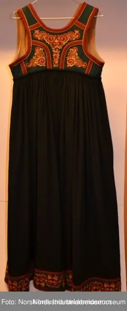 Livet er sydd fast i stakken. Stakken er rynket i linningen. Nederst på stakken er det sydd på en noe avstivet skoning. Skoningen er kantet med et grønt bånd, 1 cm. Utenpå skoningen er det festet et grønt bånd i ullklede. Klede er dekorert med plattsømbroderi og kantet med et 2 cm burgundert bånd oppe og nede. Livet er foret med et beige stoff, antagelig i bomull. Livet besår av grønt ullklede dekorert med plattsøm og kontursting. Livet er kantet med en 2 cm brede bånd.  Plattsømbroderiet er i prinsessemønster.