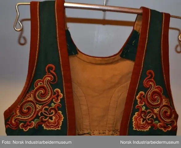 Livet er sydd fast i stakken. Stakken er rynket i linningen. Nederst på stakken er det sydd på en noe avstivet skoning. Skoningen er kantet med et grønt bånd, 1 cm. Utenpå skoningen er det festet et grønt bånd i ullklede. Klede er dekorert med plattsømbroderi og kantet med et 2 cm burgundert bånd oppe og nede. Livet er foret med et beige stoff, antagelig i bomull. Livet besår av grønt ullklede dekorert med plattsøm og kontursting. Livet er kantet med en 2 cm brede bånd.  Plattsømbroderiet er i prinsessemønster.