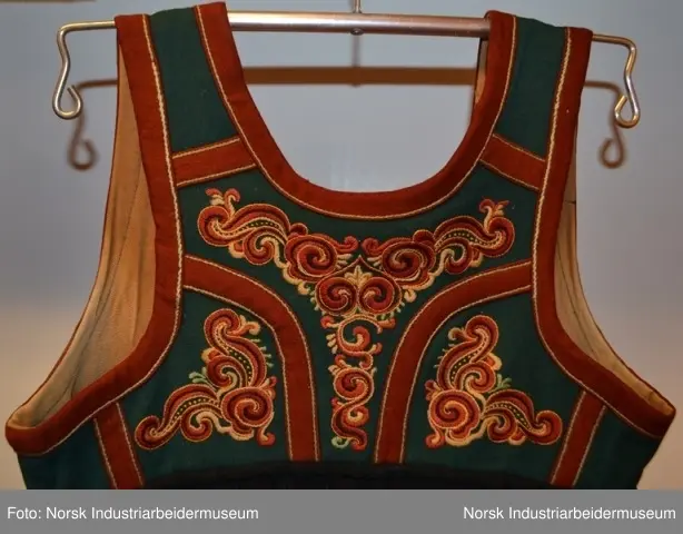 Livet er sydd fast i stakken. Stakken er rynket i linningen. Nederst på stakken er det sydd på en noe avstivet skoning. Skoningen er kantet med et grønt bånd, 1 cm. Utenpå skoningen er det festet et grønt bånd i ullklede. Klede er dekorert med plattsømbroderi og kantet med et 2 cm burgundert bånd oppe og nede. Livet er foret med et beige stoff, antagelig i bomull. Livet besår av grønt ullklede dekorert med plattsøm og kontursting. Livet er kantet med en 2 cm brede bånd.  Plattsømbroderiet er i prinsessemønster.