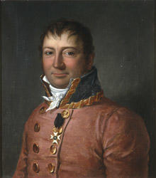 Portrett av sorenskriver Wilhelm F.K. Christie. Rød sorenskriveruniform, høy krave med gull, hvitt kalvekryss. 1 ordensstjerne.