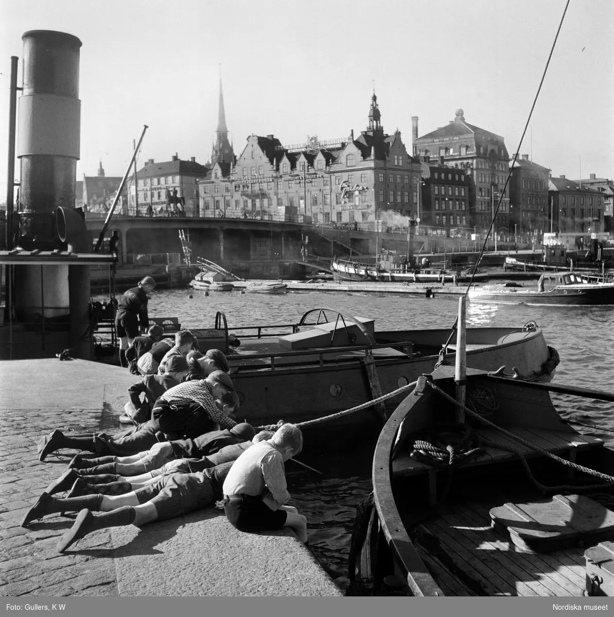 Stadsgårdskajen, Stockholm. En grupp pojkar fiskar från kajkanten.