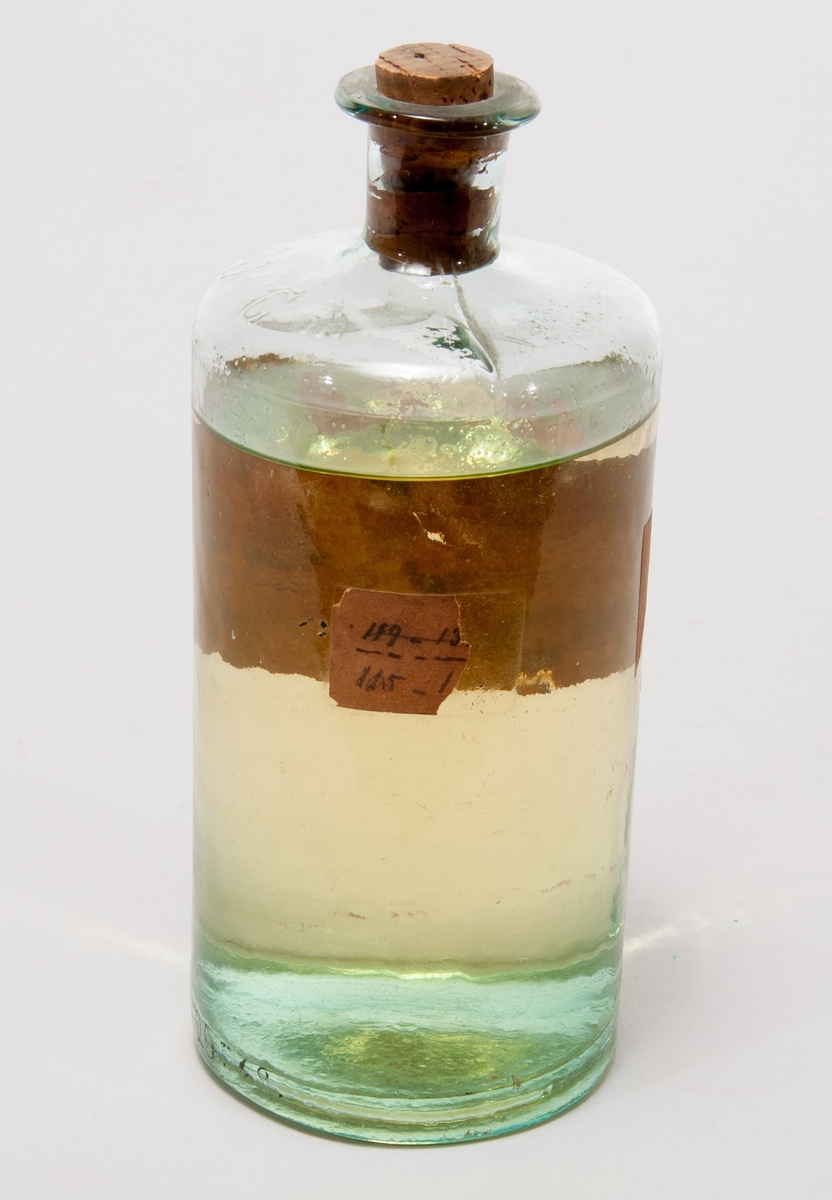 Finkelolja i  flaska av glas med etikett:  "Finkelolja från Reymersholm. II: olja, som destillerade mellan 115 grader celcius och 120 grader celcius. V.T. Alfr. Lundberg."
