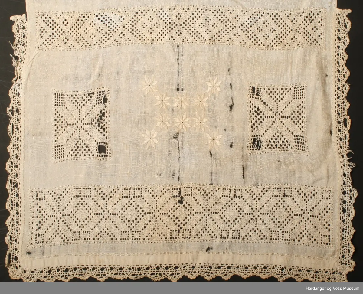 Over framstykket hekla blonde påsydd langs kanten, åttebladspirer