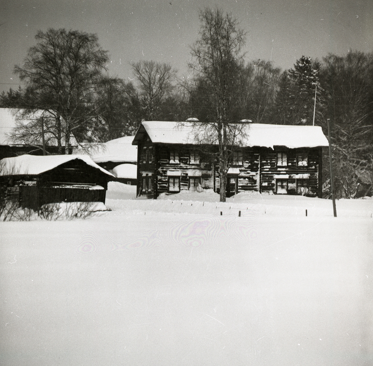 Bostadshusets snöiga yttre vittnar om en stormig vinter i Glössbo 1981. Varenda fönsterglugg är täckt av snö, taket är belamrat av en tungt snölager och snövallen längs husväggen sträcker sig upp till nedersta fönsterraden. Snön ligger orörd på åkermarken framför huset. Ladorna på gården bär lika mycket snö som bostadshuset, de enda som klarat sig från snöns tyngd är träden på gården som stolt står med bara grenar.