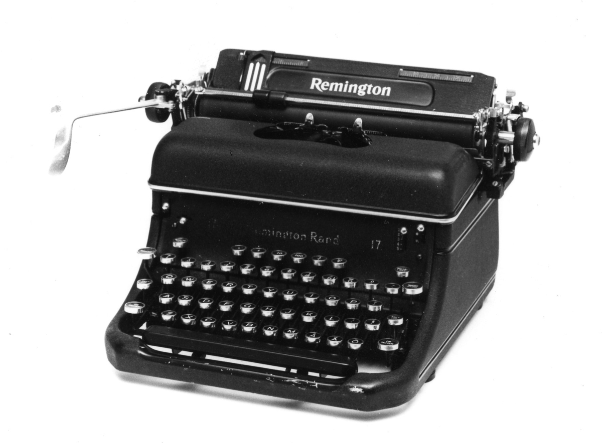 Skrivmaskin av firmamärket Remington, modell 17 nr JT 276552 med pica stil. Inköptes av postverket 1941. Ett grönt skyddsöverdrag med texten: Tillhör Statsverket, följer med maskinen.