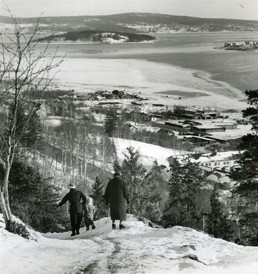Vy från Norra Stadsberget ut mot hamnen i Sundsvall, Medelpad 4 februari 1958.
Några människor försöker gå nedför det branta berget i halkan.
