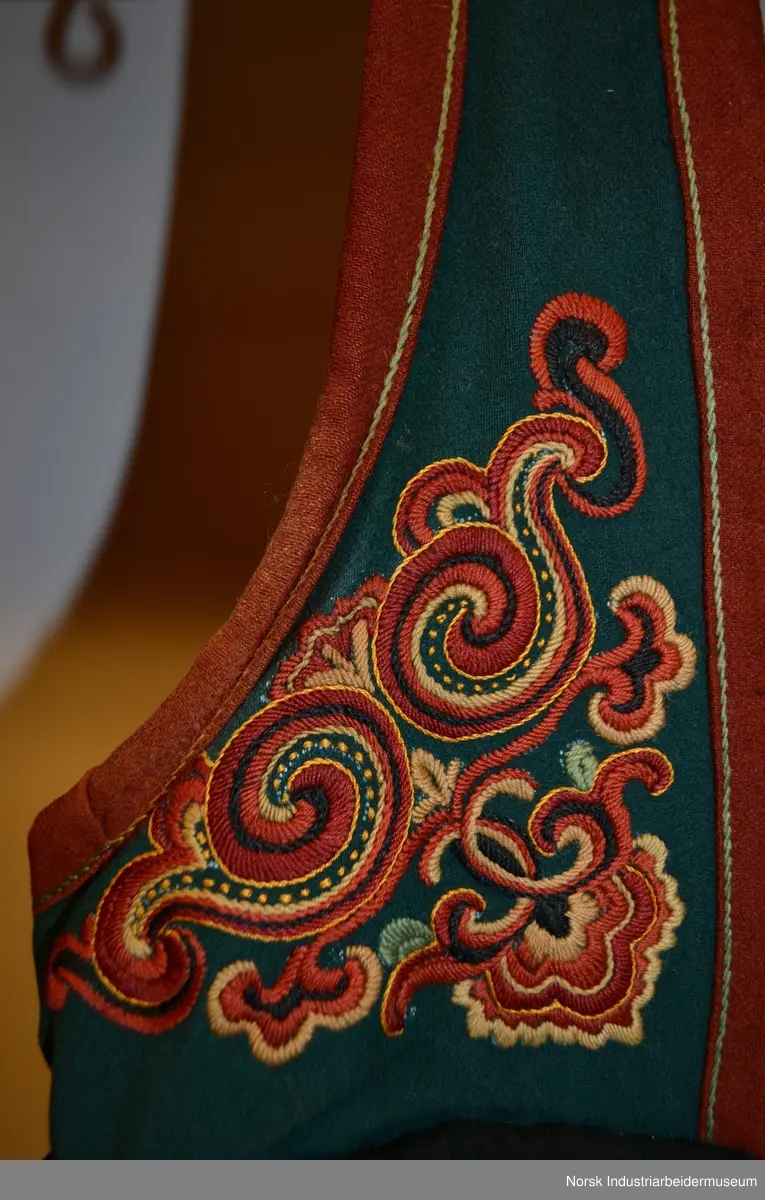 Livet er sydd fast i stakken. Stakken er rynket i linningen. Nederst på stakken er det sydd på en noe avstivet skoning. Skoningen er kantet med et grønt bånd, 1 cm. Utenpå skoningen er det festet et grønt bånd i ullklede. Klede er dekorert med plattsømbroderi og kantet med et 2 cm burgundert bånd oppe og nede. Livet er foret med et beige stoff, antagelig i bomull. Livet besår av grønt ullklede dekorert med plattsøm og kontursting. Livet er kantet med en 2 cm brede bånd.  Plattsømbroderiet er i prinsessemønster.